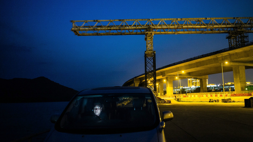 港珠澳大橋香港段建造已近尾聲，卻被爆建材化驗造假，一名香港市民夜色中在大橋建造現場觀察（圖片來源：Getty images） 