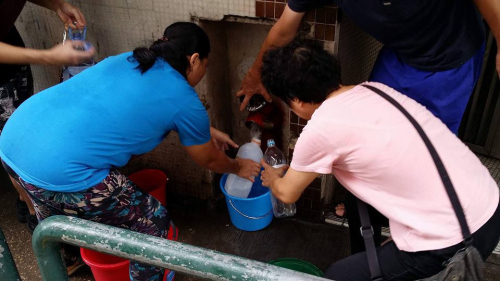 居民到公用供水处轮侯取水。