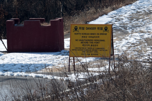 2018年2月7日，板门店的朝韩非军事区之间的一座桥梁附近的的牌子上写着小心地雷的警告。