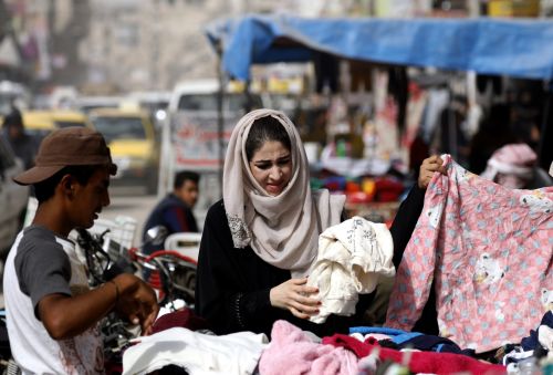 2018年10月14日，一名妇女于在叙利亚北部城市拉卡的一条市场街道买衣服。