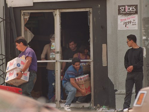 1992年洛杉矶暴动中劫持者搬着成箱的啤酒离开被砸商店。