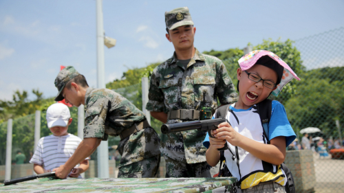 小学生们在士兵的指导下假装使用手枪作出反应。