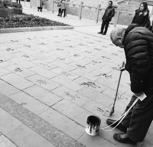 成都老人在地上写出一手好字。