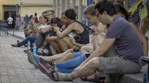 2016年10月19日，古巴人坐在哈瓦那的街道旁使用公共Wifi上網。