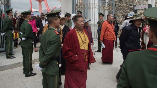 2016年7月25日，中国西北部玉树地方政府举行的节日结束，青海中国准军事警察监控一个出口，因藏人僧侣从里面走出来
