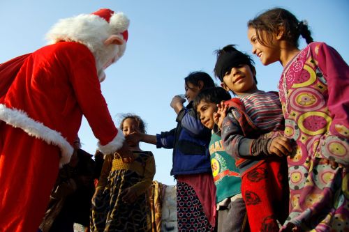 2018年12月25日，一名穿着圣诞老人服装的男子在伊拉克中心城市纳杰夫的社区向儿童分发小礼物。