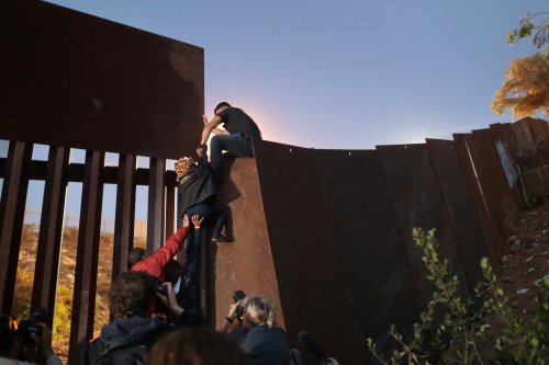 非法移民翻越美墨邊境牆。