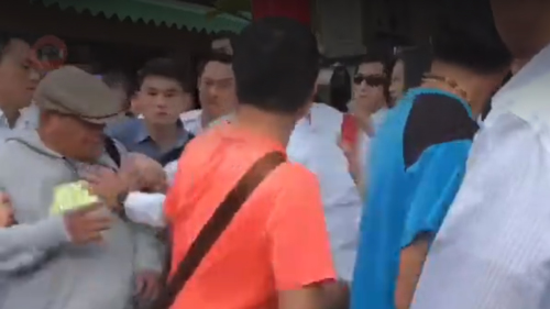 台南一名钟姓老翁16日混在排队人龙中，藉着领红包的机会近身呛蔡英文，话一出口，就被前后排队民众团团包围迅速架离