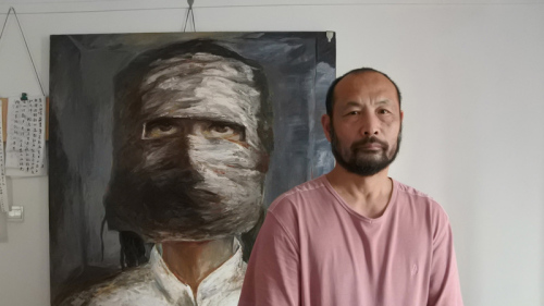 胡杰5月31日与自己的画作合影。这幅画是描绘文革中被迫害的林昭，在狱中被迫戴着头套，不能发出抗议之声。此画是根据林昭狱友描述而作。（图片来源：中央社）