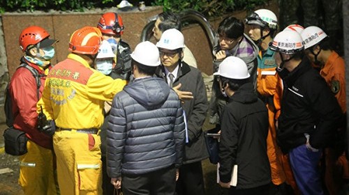 花莲救灾期间，身穿西服戴上头盔的日本专家们，与现场的救灾人员交换意见