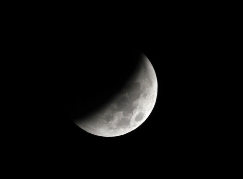 28日凌晨開始月亮持續被地球陰影遮蔽，台北民眾在雲縫中欣賞月食過程。