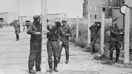 1961年8月14日，东德国家人民军的士兵竖起铁丝网，准备建造柏林墙。