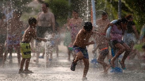 2018年8月3日，孩子们在位于马德里曼萨纳雷斯河畔的一个喷泉中玩耍降温。