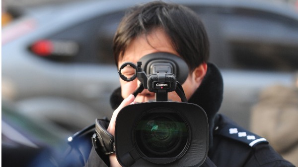 白宮这次下定决心处理历来美中对新闻自由极度不平衡的立场问题。图为一名中国警察在拍摄外国驻华记者。（图片来源：FREDERIC J. BROWN/AFP/Getty Images)