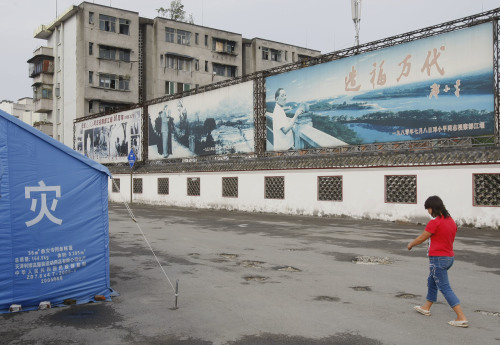 2008年7月17日，中國四川省都江堰的一名婦女在毛澤東和鄧小平宣傳廣告牌走過。