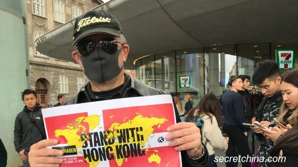 丹麥一名成功商人戴著黑口罩，舉著「支持香港」的牌子，佇立在哥本哈根鬧市區，表達對惡法的抗議。