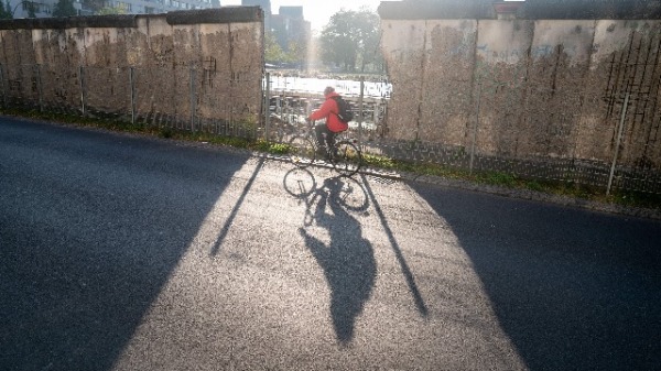 2019年11月1日，柏林墙的遗址前，有人骑自行车经过。