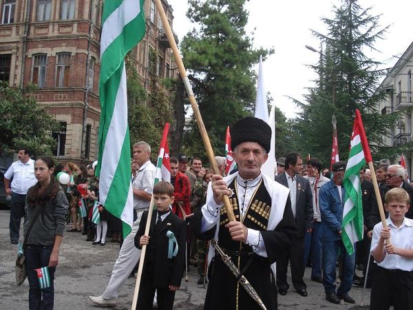 阿布哈兹人手拿共和国的旗帜在游行中。