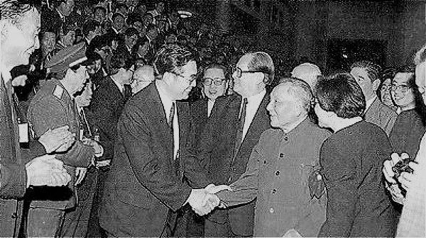 1992年10月19日，邓小平与出席中共十四大的全体代表见面，领着政治局其他常委与胡锦涛握手拍照。