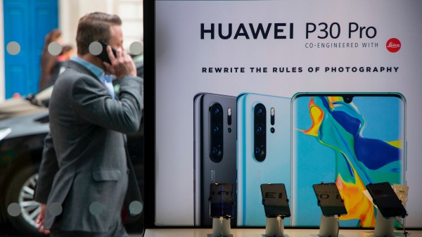 2019年4月29日，一名行人在伦敦EE电信商店走过华为产品展台。