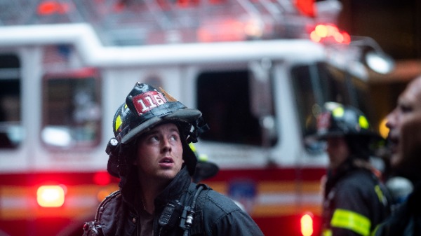 2019年6月10日，一名消防員抬頭看著一架直升機墜毀在紐約曼哈頓中城區的大樓。