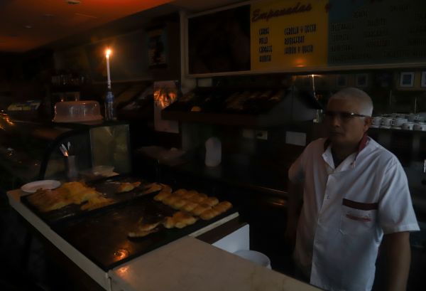 2019年6月16日，阿根廷遭遇全境停电，首都布宜诺斯艾利斯的一家面包店中的男子用蜡烛灯照亮。