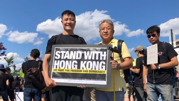 8月10日下午，在中国驻纽约总领事馆前的广场上，一群关心香港局势的华裔民众举行了声援“反送中”的示威活动。图为周锋锁（左）、宁先华（右）。