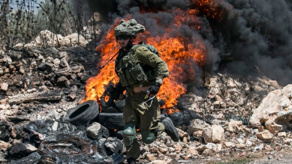 一名以色列士兵跑過燃燒的輪胎