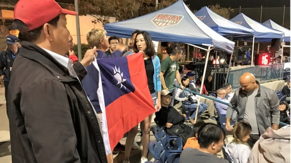 中華隊赴美國加州爾灣參加U19世界盃女壘賽 熱情僑 胞拿出大面國旗 遭到大會制止。一名美國籍的台灣女 婿（右）與大會人員爭執 遭趕出球場。