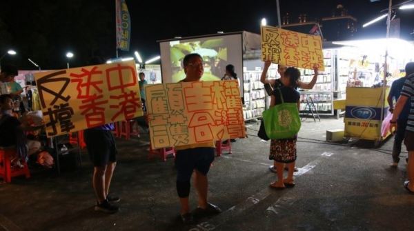 苗栗青年在头份建国夜市高举反送中、撑香港标语，并发放传单给民众。