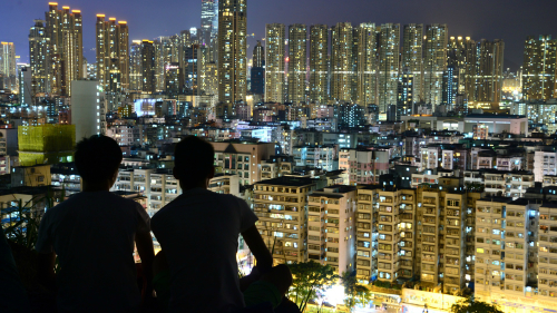 20年以来，内地生大举南下，进占本港八大院校。图为两名内地生在天台上边看香港夜景边谈话的场景。 