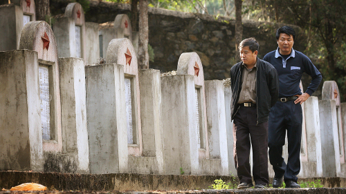 两位中国男子在边境上的士兵陵园里，这里埋葬着中越战争中死去的士兵们。