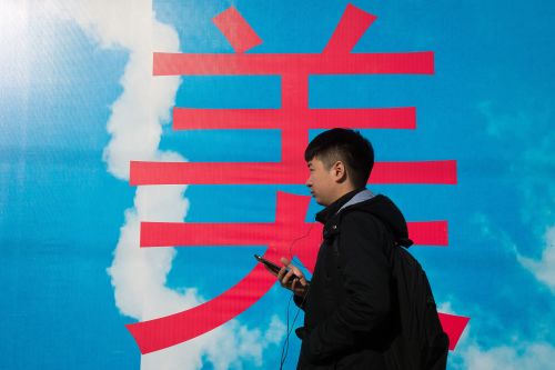 2017年11月24日，北京的一條街道上時，一名年輕男子握著他的智能手機。
