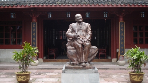 浙江桃花島上的金庸銅像，兩旁的楹聯為著名的「飛雪連天射白鹿，笑書神俠倚碧鴛」
