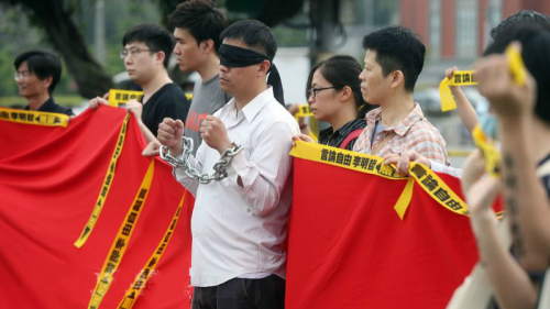 李明哲救援大队19日在总统府前举办“李明哲被抓一周年行动记者会”，并表演行动剧，象征李明哲被关押失去自由。