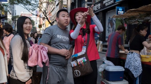 2017年5月18日，导游在给游客讲解韩国首尔明洞购物区。