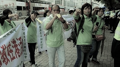 “香港青关会”在梁振英上任前不久成立，并在成立后的第二天，便把中共“610”系统在中国大陆使用的各类诽谤诬蔑法轮功的横幅、展板等，原版照搬到香港景点和闹市区