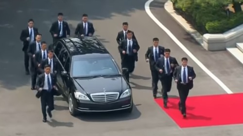 2018年6月12日，美朝在新加坡舉行「川金會」，朝鮮護衛人員在一輛載有金正恩的汽車旁慢跑。
