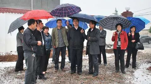 时任河南汝州市委书记李全胜下雨天背着双手，两人为他撑伞。（网络图片）