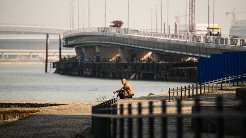 一名老翁蹲坐在港珠澳大桥工地前，感受片刻的宁静。