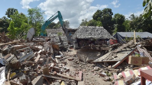 2018年8月12日，印尼龍目島地震災區，工人用挖掘機清理被地震破壞的商店。