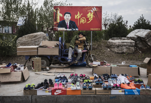 2017年4月9日，石家庄一个小贩在立有”中国梦“的标志前摆摊卖鞋。