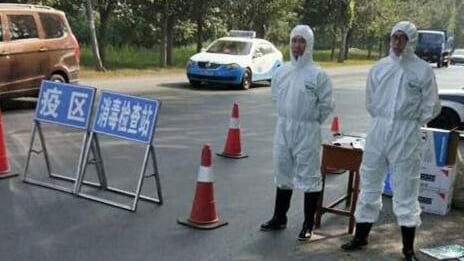 辽宁沈阳在发生猪瘟疫情的地区设置临时消毒检查站，有身穿保护衣的人员在场戒备。（视频截图）