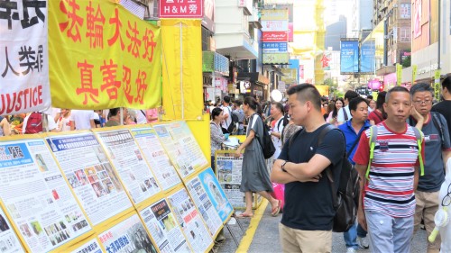 一名香港市民正在專心觀看法輪功街站展示的展板