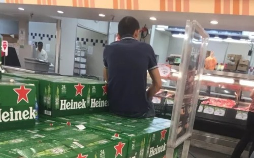 华人坐在超市啤酒箱上