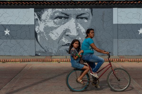 2018年11月27日，一位委内瑞拉妇女和小孩在查韦斯巨幅画像前。