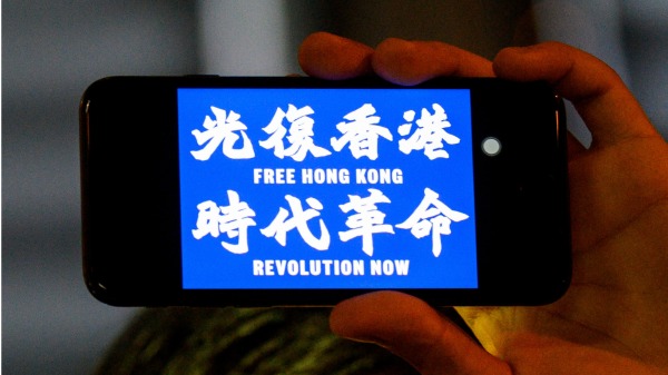 抗争者用手机显示出光复香港 时代革命的口号。