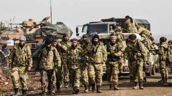 美国从叙利亚北部撤出其余军队后，土耳其大举进攻叙利亚北部。图为土耳其军（后）伙同他所支持的叙利亚自由军（前），在2018年1月进犯库尔德武装组织“人民保护部队”。（BULENT KILIC/AFP/Getty Images)