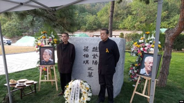 2019年10月18日，趙紫陽夫婦墓碑前擺放著出席骨灰安葬儀式的親友們獻的鮮花。趙紫陽之子趙二軍（右）立於碑前。