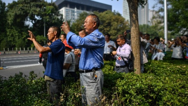 2019年10月1日，民众在北京天安门广场周围建立的安全区内观看军事游行。